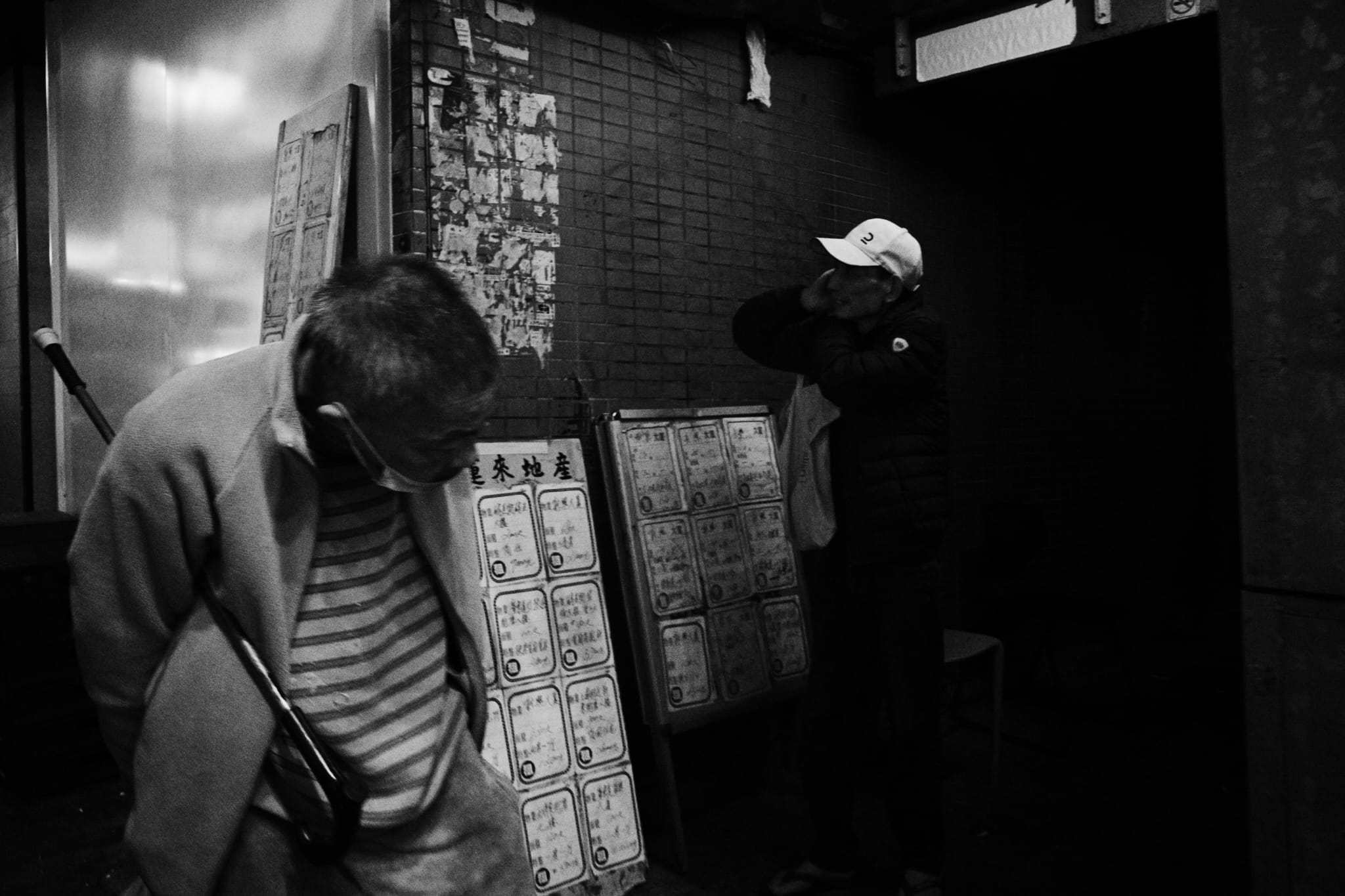 Two people waiting beneath street signs