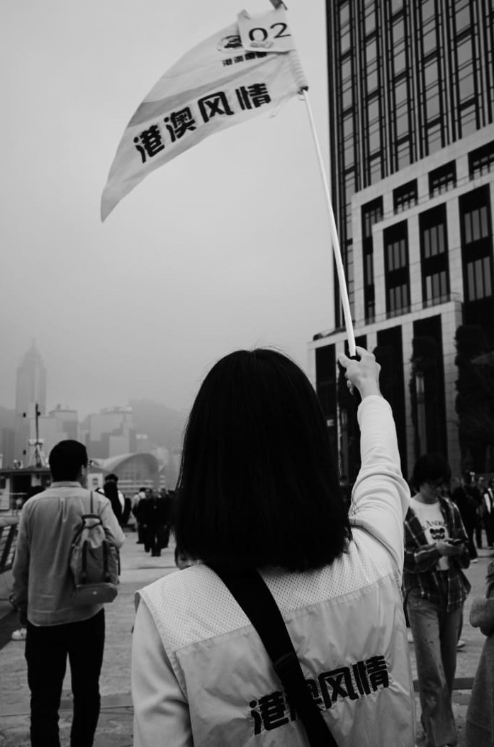 A person carrying a flag through a public square