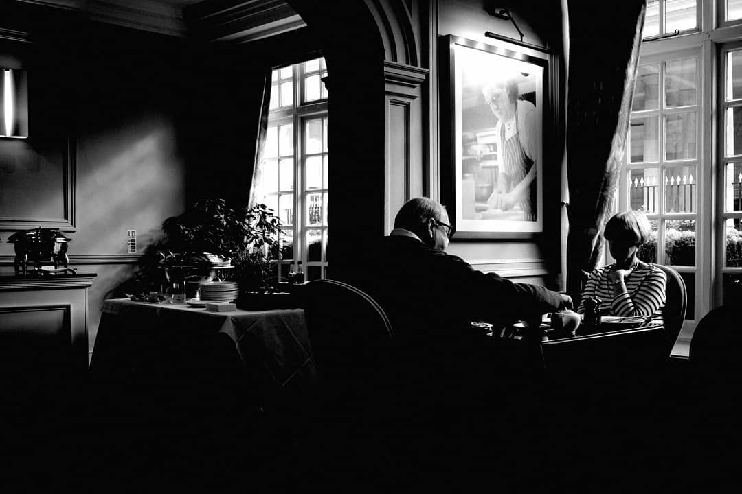 Two people seated in a shadowed dining room