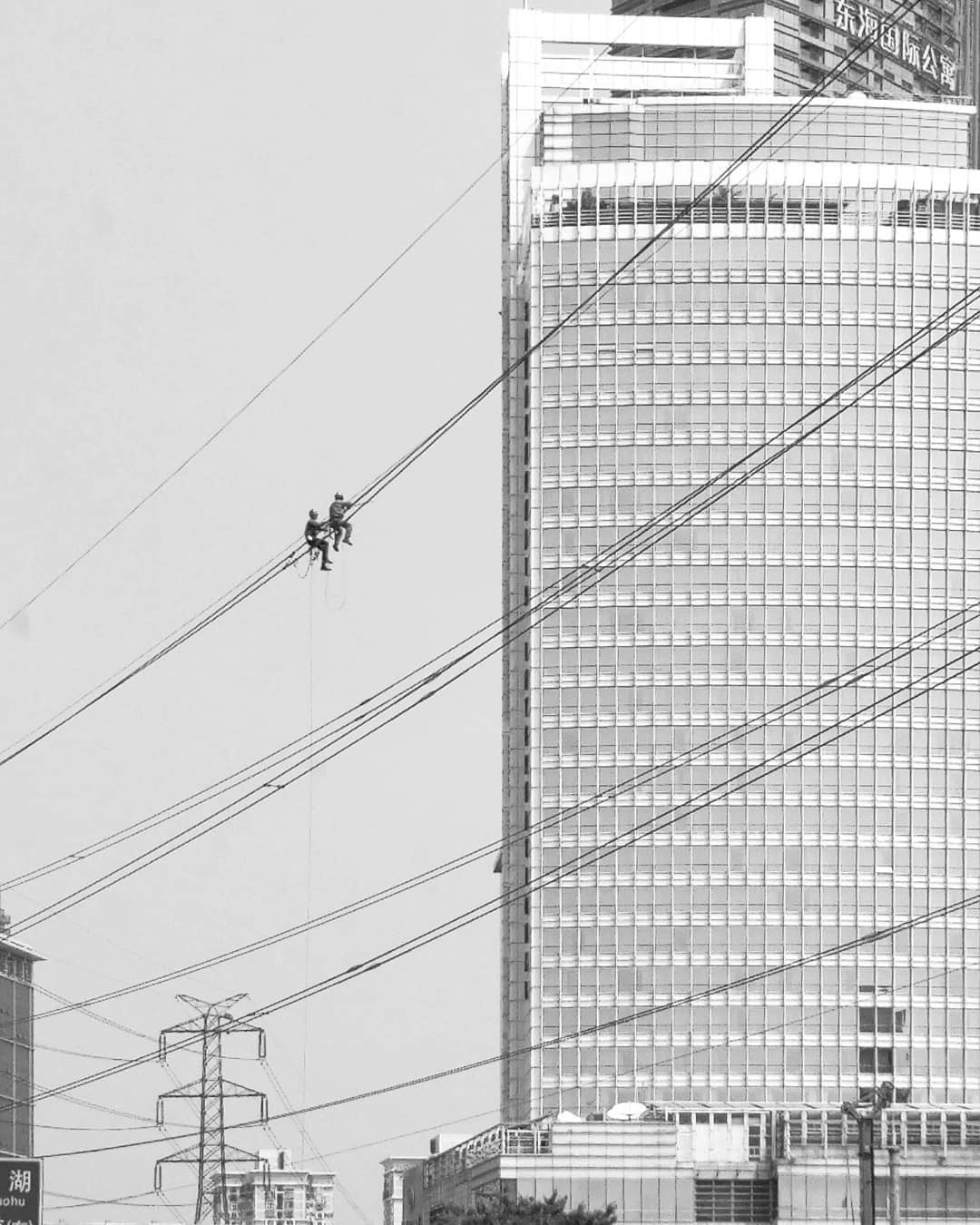 Workers suspended on cables beside a tall building