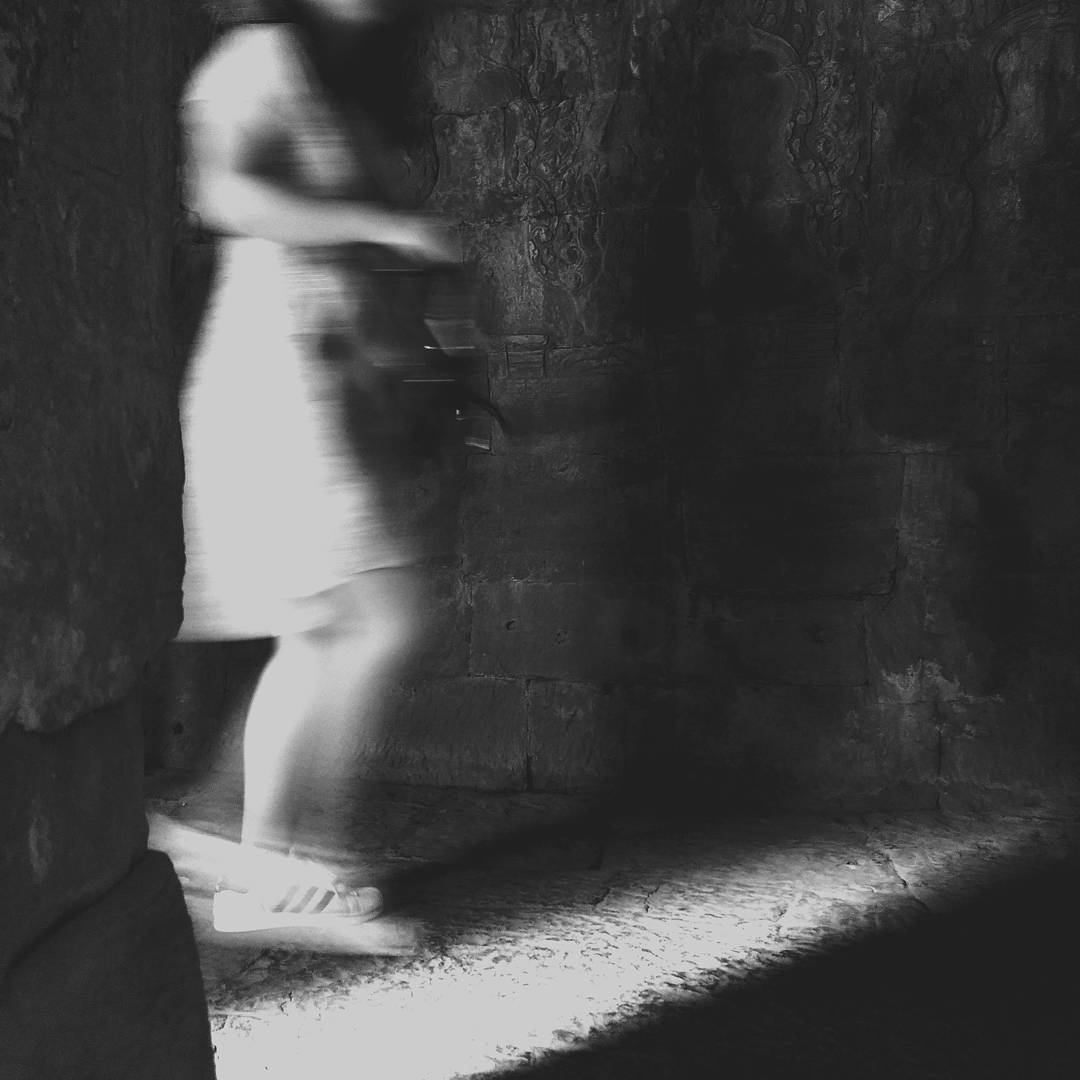 A blurred figure walking through a dark interior