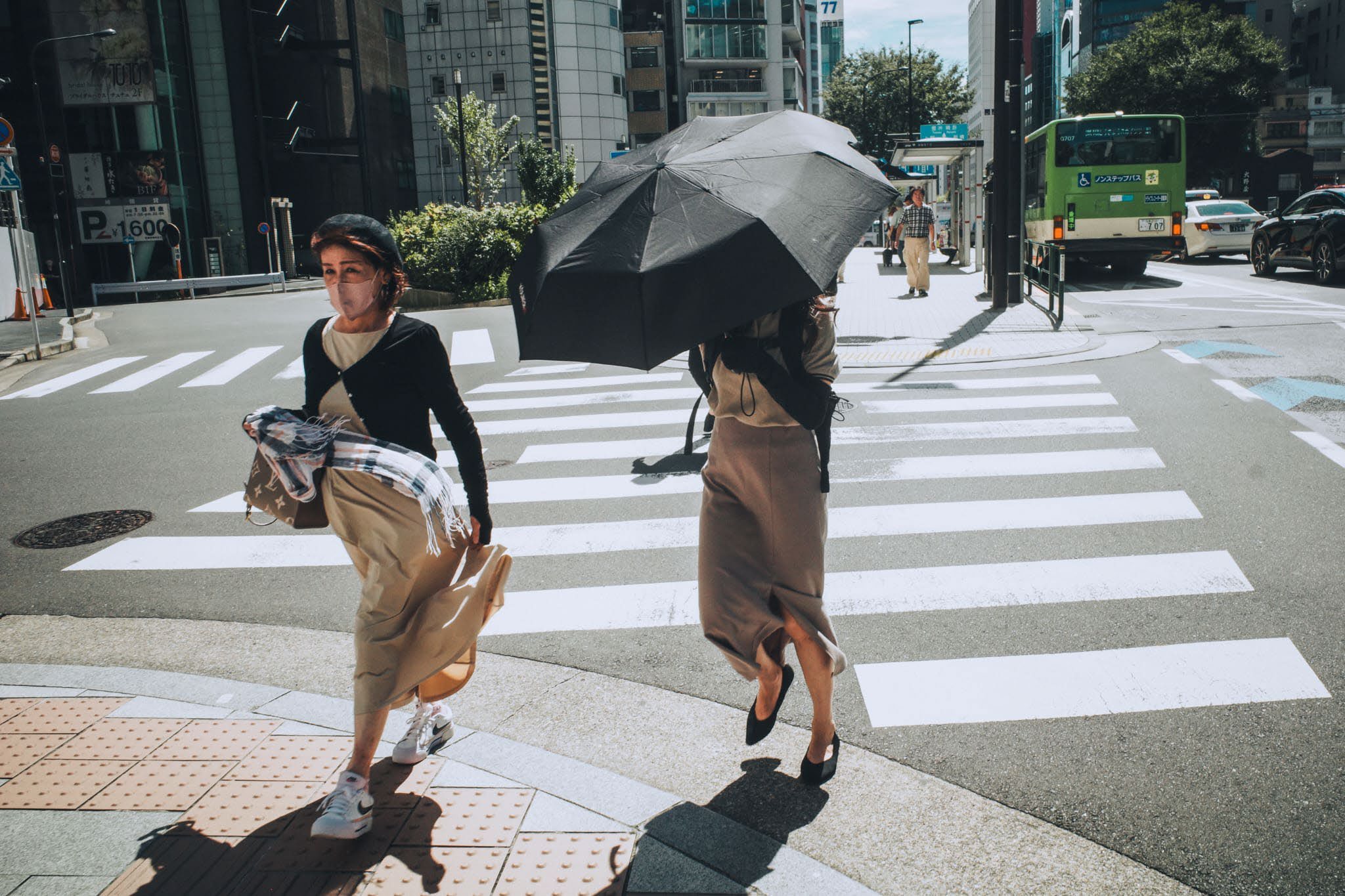 People crossing a street beneath an umbrella