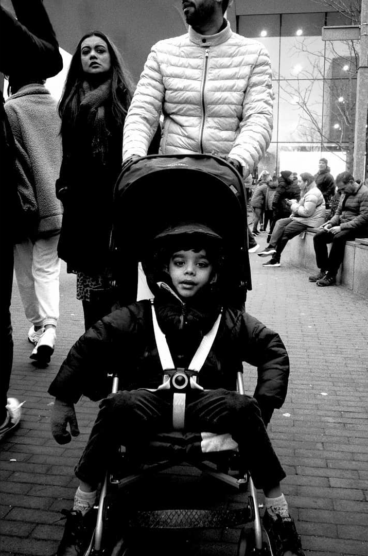A child seated in a stroller among pedestrians