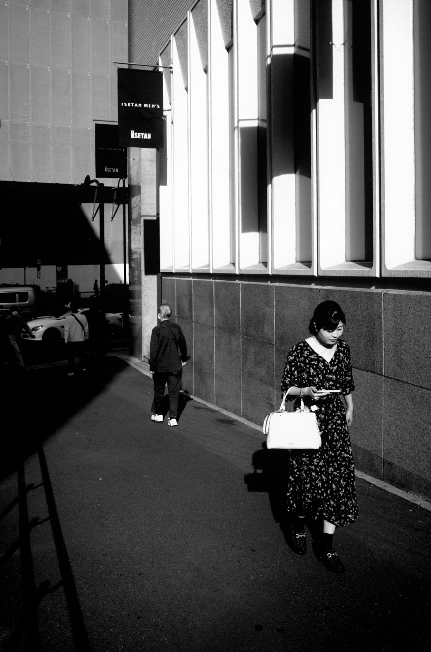 A figure walking between bright building columns