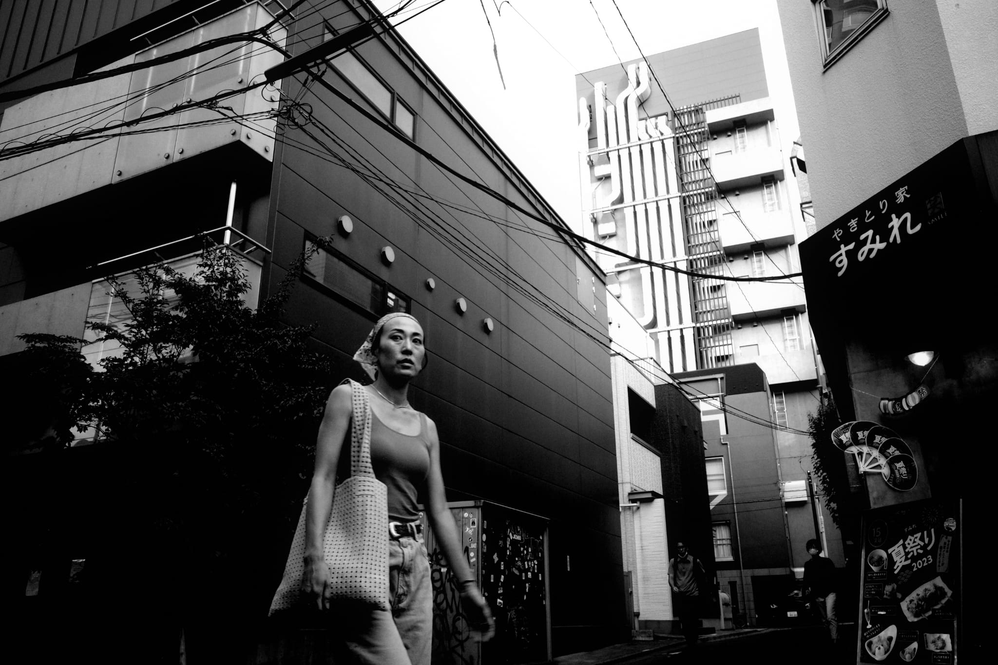 A woman walking between tall city buildings
